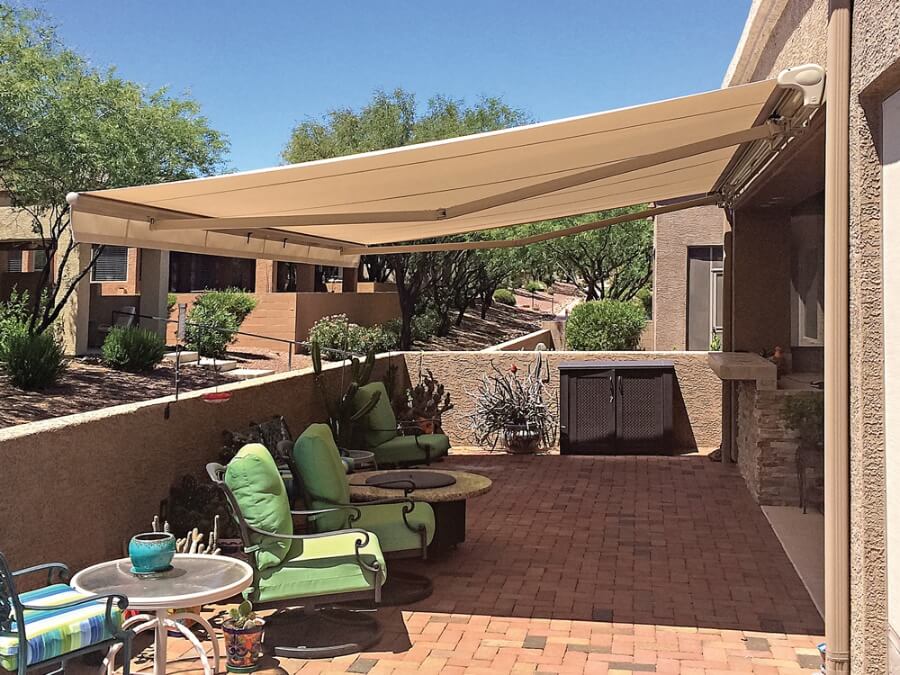 A private back yard patio with a retractable tan awning covering the sunny space.