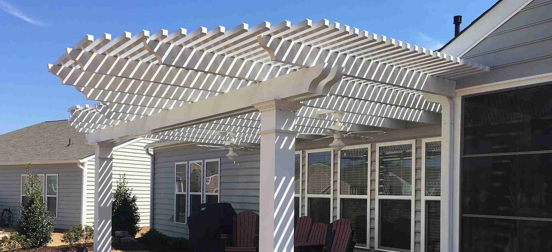 A white wooden pergola attached to a back porch area