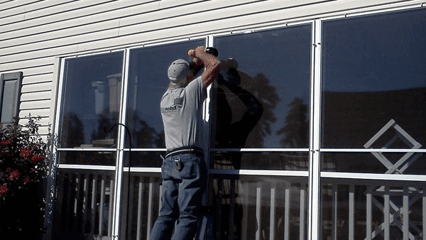 Screenmobile Tech servicing a window screen affixed to a home.