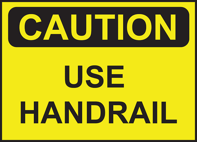 Black lettering on a yellow caution sign saying use handrail