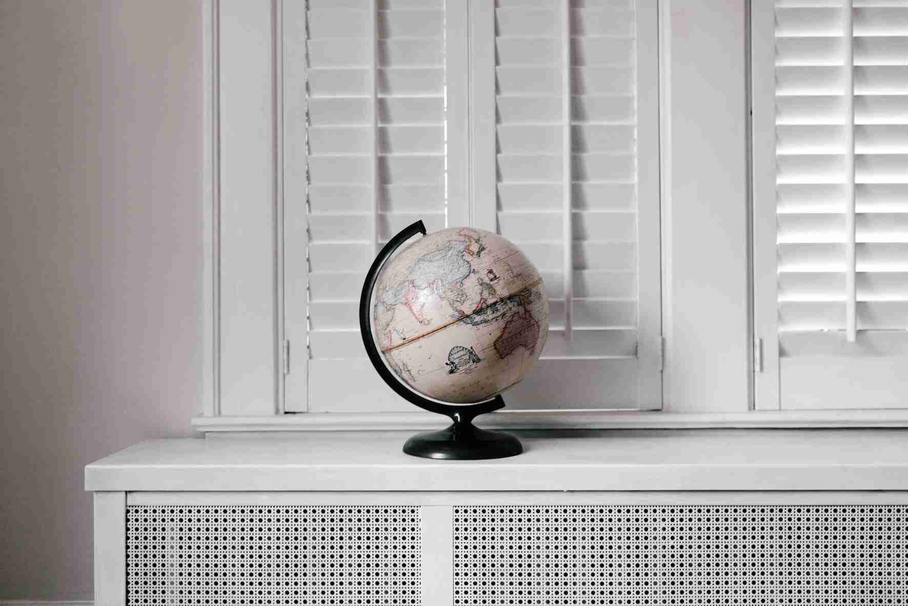 A black and white globe sits in front of window shutters